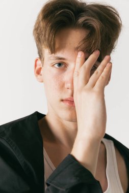 - Yakın çekim. Beyaz stüdyo arka planında izole edilmiş yakışıklı erkek portresi. Moda anlayışı, gençlik, duygular, yüz ifadesi, reklam. Moda erkek modelleri gündelik kıyafetlerle poz veriyor. Sakin, ciddi görünüyor.