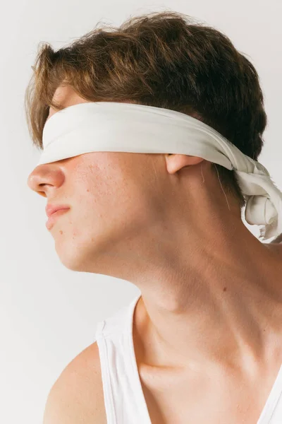 Obscurity. Handsome man with blindfold isolated on white studio background. Concept of fashion, youth, emotions, facial expression, ad. Fashion male model in casual style clothes posing.