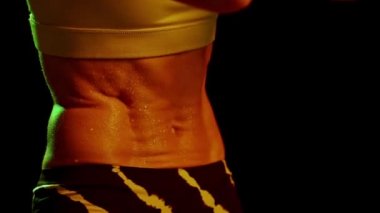 Spor yaparken terli bir kadın. Neon 'daki koyu dumanlı spor salonunda spor eğitimi alan çelik karın kaslarıyla yakın çekim. Güzellik, gösteri ve spor, aksiyon, güç, enerji konsepti. Spor yapan kadınlar. 4k, video