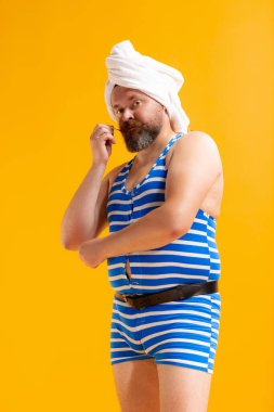 Spa zamanı. Eski tarz çizgili mayolu komik şişman sakallı adamın komik portresi sarı arka planda eğleniyor. Yaz, sahil, dinlenme ve eğlence zamanı konsepti.