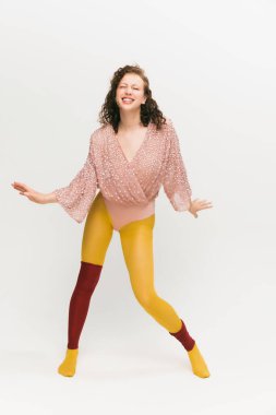 Dans ediyorum. Beyaz arka planda yenilikçi tarzda afallamış güzel bir kızın portresi. Parlak sarı taytlı şık bir model. Canlı tarz, güzellik, nonoş, ucube, moda konsepti.