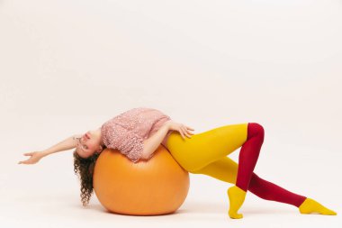 Rahatlayın ve gerinin. Avangard tarzı giyinmiş, beyaz arka planda eğlenen oldukça komik bir genç kız. Fitness, canlı tarz, güzellik, nonoş, ucube, moda konsepti.