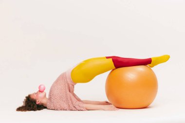 Rahatlayın ve gerinin. Avangard tarzı giyinmiş, beyaz arka planda eğlenen oldukça komik bir genç kız. Fitness, canlı tarz, güzellik, nonoş, ucube, moda konsepti.