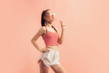 Yaz zamanı. Şortlu ve şeftali rengi arka planda soyutlanmış güzel bir kız. Güzellik, sanat, moda, duygular, gençlik kavramı. İlan için alanı kopyala