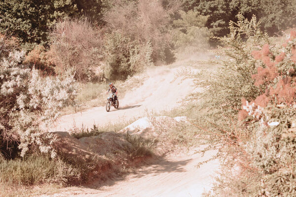 Professional motorcycle rider training on Enduro motorcycle at steppe or desert area, outdoors at hot summer day. Motocross sport, speed, action