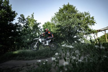 Enduro motosikleti süren Ukraynalı profesyonel motosikletçi, sıcak yaz gününde açık havada. Motokros sporu, hız, motor. 11 Haziran 2022