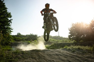 Orman yolu, yol. Profesyonel motosiklet sürücüsünün yarışma sırasında Enduro motosikletine binerken canlı çekimi, yaz akşamları açık havada. Motokros sporu, hız, aksiyon
