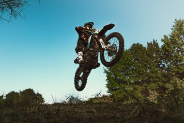 Uçuş. Enduro motosikleti süren Ukraynalı profesyonel motosikletçi, sıcak yaz gününde açık havada. Motokros sporu, hız, motor. 11 Haziran 2022