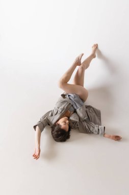 Duygular. Gri arka planda izole edilmiş iç çamaşırlı ve palto danslı genç bir kadının dinamik portresi. Sanat, hareket, hareket, esneklik, ilham konsepti. Tek kişilik performans