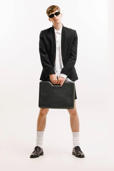偏心的 一个年轻时尚的男人 穿着黑色短裤和夹克的学生在白色背景上摆出孤立的姿势 现代商务服装 青年文化 销售和广告的概念 — 图库照片