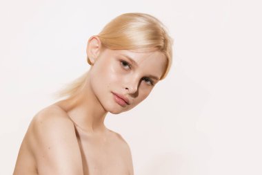 Well-kept skin. Young beautiful girl with blond glossy hair and without makeup isolated on white studio background. Youth, spa, cosmetics, beauty and skin care concept. Copy space for ad
