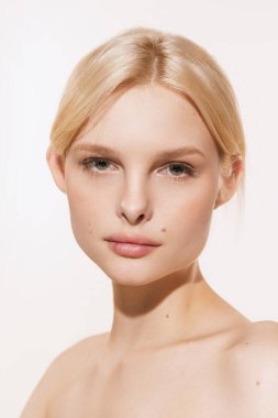 Doğal güzellik. Beyaz stüdyo arka planında izole edilmiş kameraya bakan sarı saçlı, yakın arkadaş canlısı genç bir kız. Spa, kozmetik, refah ve cilt bakımı konsepti. İlan için alanı kopyala