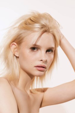 Cazibeli bak. Beyaz stüdyo arka planında izole edilmiş kameraya bakan sarı saçlı, yakın arkadaş canlısı genç bir kız. Spa, kozmetik, refah ve cilt bakımı konsepti. İlan için alanı kopyala