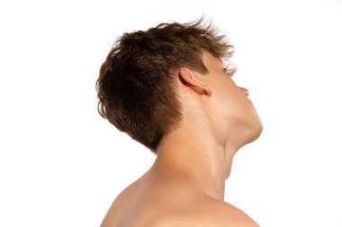 Boyun ve omuzlar. Genç ve yakışıklı bir çocuk. Beyaz stüdyo geçmişinde iyi korunmuş bir cildi var. Genç cilt bakımı, sağlık, sorunlu cilt için kozmetik, gençlik kavramı. Sanat, moda, reklam.