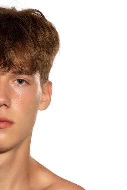 Yüzün yarısı. Beyaz stüdyo arka planında izole edilmiş yakışıklı bir adamın yakın plan portresi. Erkek sağlığı, kendine bakım, vücut ve cilt bakımı kavramı. Erkek model kameraya bakıyor.