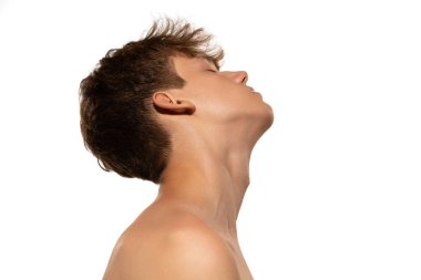 Genç ve yakışıklı bir çocuk. Beyaz stüdyo geçmişinde iyi korunmuş bir cildi var. Genç cilt bakımı, sağlık, sorunlu cilt için kozmetik, gençlik kavramı. Sanat, moda, sağlıklı yaşam tarzı ve reklam.