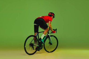 Arkadan bak. Genç sporcu, spor üniformalı bisikletçi ve yeşil arka planda izole edilmiş koruyucu kask eğitimi. Aktif yaşam, dinlenme, seyahat, enerji ve spor kavramı. İlan için alanı kopyala