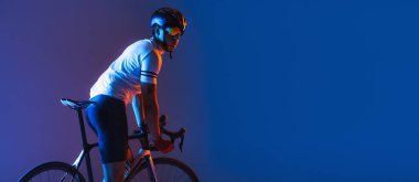Flyer with male cyclist riding bicycle wearing cycling shorts and protective helmet isolated on dark blue background in neon. Concept of active life, rest, travel, energy, sport. Copy space for ad