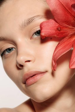 Şefkatli bir bakış. Beyaz stüdyo arka planında izole edilmiş çiçekli güzel bir genç kızın yakın plan portresi. Çıplak renk, diyet, kozmetik, doğal güzellik ve estetik kozmetik konsepti. Uzayı kopyala