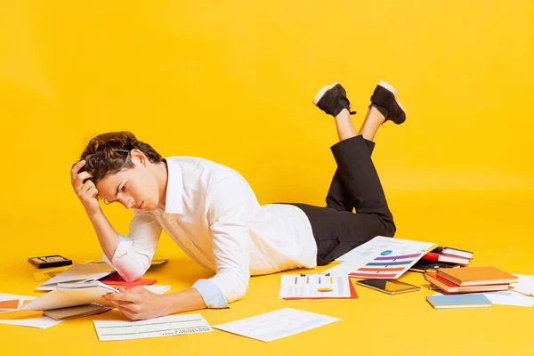 困难的任务 穿着商务服装的男生或女生躺在地板上 在黄色的背景下独立做作业 考试准备工作 学习和青年的概念 — 图库照片