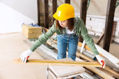 Repair work. Young woman, professional builder makes room repairs using different work tools. Gender equality. Work, occupation, apartment renovation. Pretty girl in work clothes