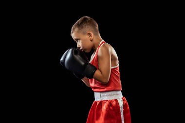 Genç boksör, sportif çocuk eğitimi karanlık arka planda izole edilmiş. Spor anlayışı, hareket, öğrenim, yaşam tarzı. Çocuk yumruk pratiği yapıyor. İlan için alanı kopyala