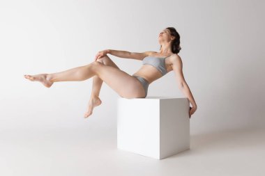 Şefkat. Gri stüdyo arka planında, rahat pamuklu iç çamaşırlı genç ve tapılası bir kadın. Güzellik, vücut ve cilt bakımı, tüy dökümü, epilasyon, sağlık, kaplıca, kozmetik, reklam