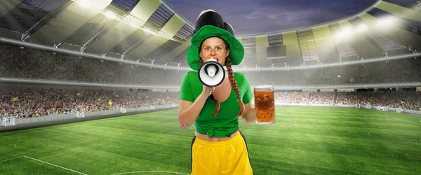 Happy excited woman in green yellow football kit holding beer mug and megaphone supports favorite team. Emotions, drinks, hobby, fans, competition, sport, oktoberfest concept. St. Patricks Day