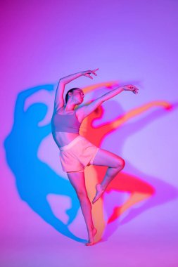 Genç sportif kız eğitimi, renkli gölgeli neon ışıkta, gradyan stüdyo arka planında izole edilmiş. Atletik ve zarif. Modern spor, aksiyon, fitness, yoga, hareket, gençlik konsepti.