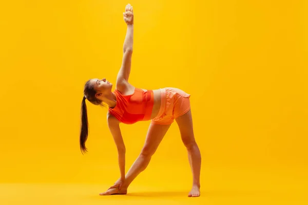 노란색 배경에서 스트레칭 운동을 바지를 소녀의 현대의 스포츠 젊음의 — 스톡 사진