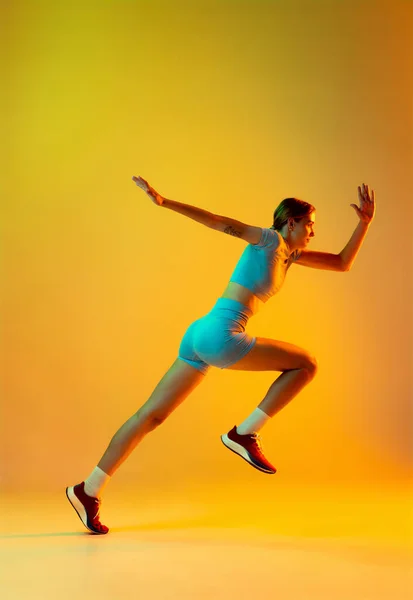 Runner. Professional longjumper. One female athlete in sports uniform jumping isolated on yellow background. Concept of sport, action, motion, speed, healthy lifestyle. Copy space for ad