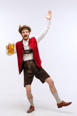 Dans ediyor. Oktoberfest 'in portresi şapkalı, geleneksel Bavyera ya da Alman kıyafetleri giymiş elinde bira kupası olan duygusal bir adam. Alkol, gelenekler, tatiller, festival konsepti. İlan için alanı kopyala