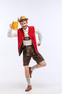 Dans ediyorum. Oktoberfest 'in portresi şapkalı, geleneksel Bavyera ya da Alman kıyafetleri giymiş elinde bira kupası olan duygusal bir adam. Alkol, gelenekler, tatiller, festival konsepti. İlan için alanı kopyala