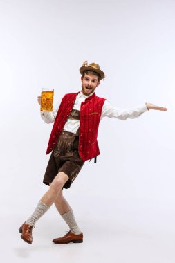 Welcome to holiday event. Young cheerful man in hat, wearing traditional Bavarian or german clothes, holding beer mug. Alcohol, traditions, holidays, oktoberfest fest concept. Copy space for ad