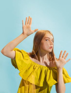 Surat asma. Genç, güzel bir kız, açık mavi arka planda şeffaf cama yaslanmış bir öğrenci. Yakın plan. İnsan duyguları kavramı, yüz ifadesi, müzik, reklam, moda, güzellik.