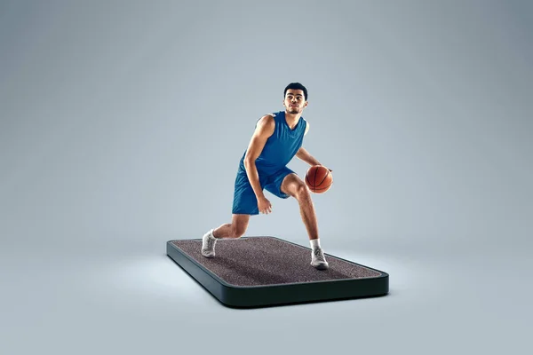 Streetball. Online sports competitions. Professional basketball player playing basketball on 3d device screen over colored background. Show, games, online events, media, betting, ad. Collage