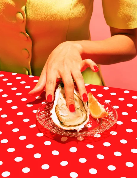 Colorful image of delicious oyster and female hands isolated on red tablecloth. Yummy dinner. Food pop art photography. Vintage, retro style. Complementary colors, Copy space for ad, text