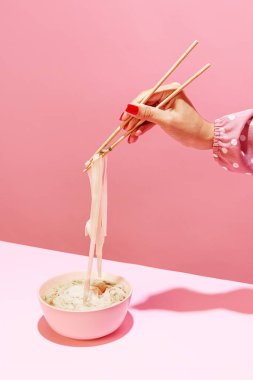 Baharatlı bir tat. Pembe arka planda izole edilmiş eriştenin enfes görüntüsü. Yemek çubuklarıyla Japon mutfağı yemek. Antika, eski tarz. Tamamlayıcı renkler, reklam ve metin için alanı kopyala