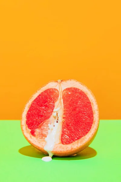 Food pop art photography. Image of juicy grapefruit isolated on green orange background. Sweet and sour taste. Vintage, retro style. Complementary colors, Copy space for ad, text