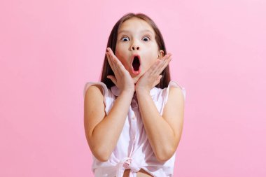 Wonder, suprise. Emotional little charming girl, kid wearing blouse isolated on pink background. Concept of children emotions, fashion, beauty, school and ad concept.