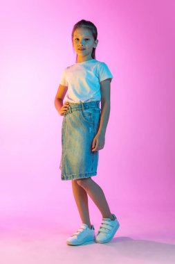 Çocuk modası. Mutlu küçük güzel bir çocuk, günlük kıyafetli liseli kız pembe arka planda izole edilmiş. Çocuk duyguları, güzellik anlayışı, okula dönüş ve reklam.