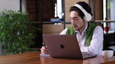 Online studying. Young man, freelancer working on laptop computer at home office. Student typing on laptop keyboard at office workplace. Portrait of positive business man looking at device screen.