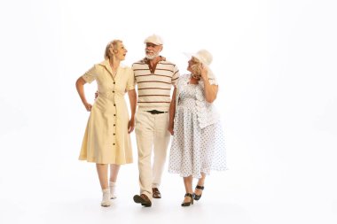 Romantic walks. Handsome senior man and two charming women in vintage retro style outfits isolated on white background. Concept of relations, family, 1960s american fashion style and art.