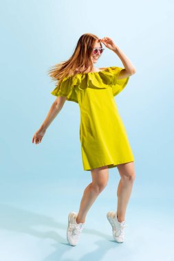 Fashion. Studio shot of young beautiful blonde in summer yellow dress isolated on light blue background. Concept of beauty, art, style, youth, healthy lifestyle. Copyspace for ads, text, sales offer.