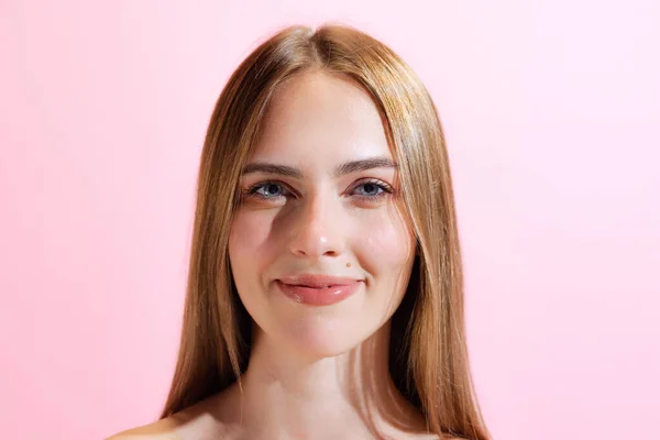 Calm look. Closeup face of young beautiful girl, student looking at camera isolated on pink background. Concept of beauty, art, fashion, youth, healthy lifestyle. Copyspace for ads, text