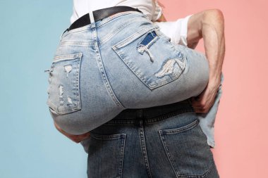 Closeup female buttocks in denim blue jeans over blue and pink trendy color background. Human emotions, youth, love and lifestyle concept. Heart shape