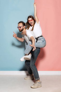 Youth. Young crazy man and astonished girl having fun isolated on blue and pink trendy color background. Human emotions, joy, enjoy, love and lifestyle concept