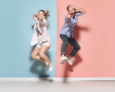 Silly mood. Couple of young funny and happy man and woman having fun isolated over blue and pink background. Human emotions, youth, love and active lifestyle concept