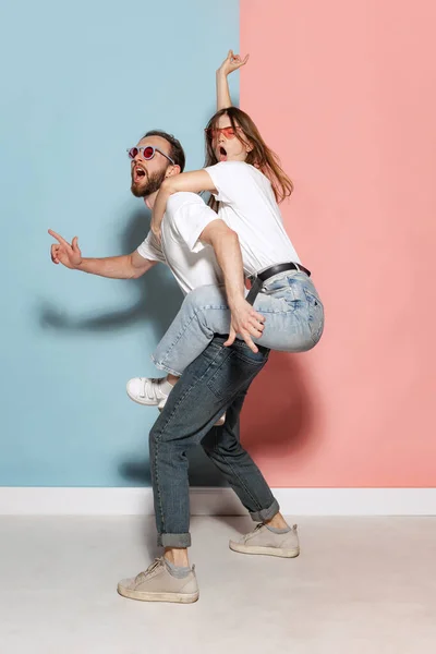 Diversity. Young crazy man and astonished girl having fun isolated on blue and pink trendy color background. Human emotions, youth, love and lifestyle concept