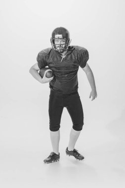 Athlete. Black and white portrait of american football player in vintage style sports uniform isolated on white background. Concept of sport, eras comparison, timeless traditions, skills and ad